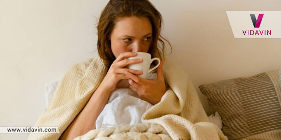 دختر بیمار در حال نوشیدن چای در بستر بیماری